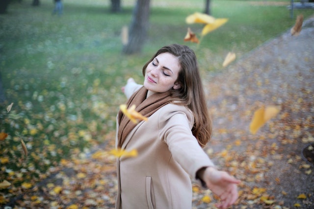 Frau ist glücklich im Blätter Regen